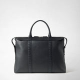 Front view: The SOFT BRIEFCASE IN CACHEMIRE LEATHER AND MOSAICO is shown with two handles and a zipper against a light background; black leather surface with vertical Mosaico decorative strips.