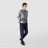 Frontal view: A person holds the CLUTCH IN CACHEMIRE LEATHER AND MOSAICO in navy blue leather with a wrist handle loosely in the right hand, elegantly dressed.