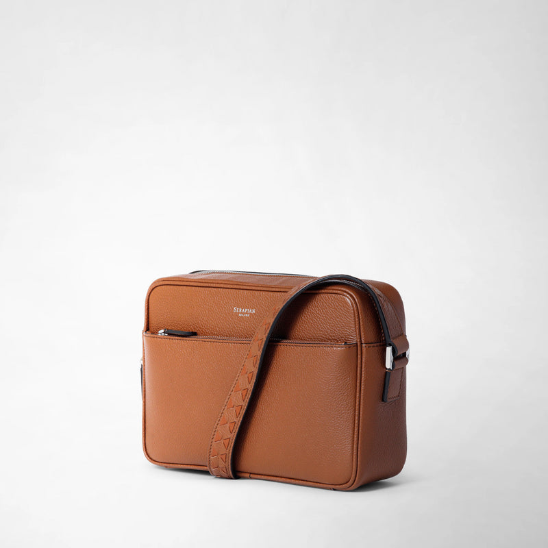 Frontal view: EAST WEST CROSSBODY BAG IN CACHEMIRE LEATHER features a rectangular tobacco brown leather crossbody bag with a textured finish, front zip pocket, and adjustable shoulder strap. The word &#39;SERAPIAN&#39; appears in small letters on the front pocket.