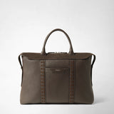 Front view: SOFT BRIEFCASE IN CACHEMIRE LEATHER AND MOSAICO stands upright with two handles; espresso-colored leather, geometric Mosaico strips, and a front compartment. Logo: “SERAPIAN MILANO”.