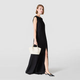 横からのビュー：MOSAICO MICROCHAIN製ミニSECRETバッグ、クリーム色の織りMOSAICO柄と細いマイクロチェーンが施されたミニバッグを、黒いイブニングドレスのモデルが短いハンドルで手に持っている。