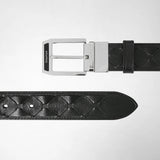 Front view: BELT IN MOSAICO lies against a light background, featuring black geometrically embossed leather and a shiny silver pin buckle marked “SERAPIAN”.