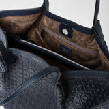 Detail view: VERTICAL SECRET TOTE BAG IN MOSAICO shows a close-up of the interior and top edge of a navy blue woven leather tote bag, revealing multiple compartments, a zipped pocket, brown suede lining, and 'SERAPIAN MILANO MADE IN ITALY' printed inside.