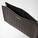 Detail view: CLUTCH IN MOSAICO lies open, showing the dark gray-brown woven leather, zipper, and black lining. Visible lettering: “SERAPIAN MILANO,” “SERAPIAN,” and “MADE IN ITALY.”