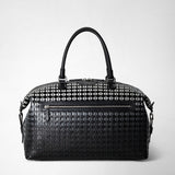 Front view of the TRAVEL BAG IN MOSAICO, an elegant black travel bag made of Chiaroscuro Mosaico nappa leather with woven pattern, top handles, and front zip pocket.