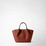 Front view: MINI SECRET BAG IN MOSAICO is presented against a light background; brick-red, mosaic-woven leather, a short handle, and the “SERAPIAN MILANO” logo are visible.