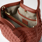 Detail view: MINI SECRET BAG IN MOSAICO shows the brick-red woven leather exterior and suede interior compartment with a gold zipper; the label reads “SERAPIAN” and “MADE IN ITALY”.