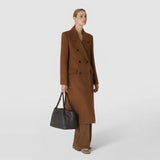 Angled view: A woman carries the SMALL SECRET TOTE BAG IN RIBBON MOSAICO in dark woven nappa leather on her arm; the roomy bag displays a striking three-dimensional pattern.