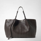 Front view: SECRET TOTE BAG IN RIBBON MOSAICO stands upright with long handles, showing its dark brown, intricately woven leather texture; “SERAPIAN MILANO” is written on the bag.