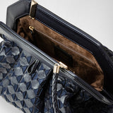 Detail view: SECRET CLUTCH BAG IN MOSAICO features a close-up of midnight blue woven nappa leather, showcasing its unique structure and brown suede-lined interior with a zip pocket.