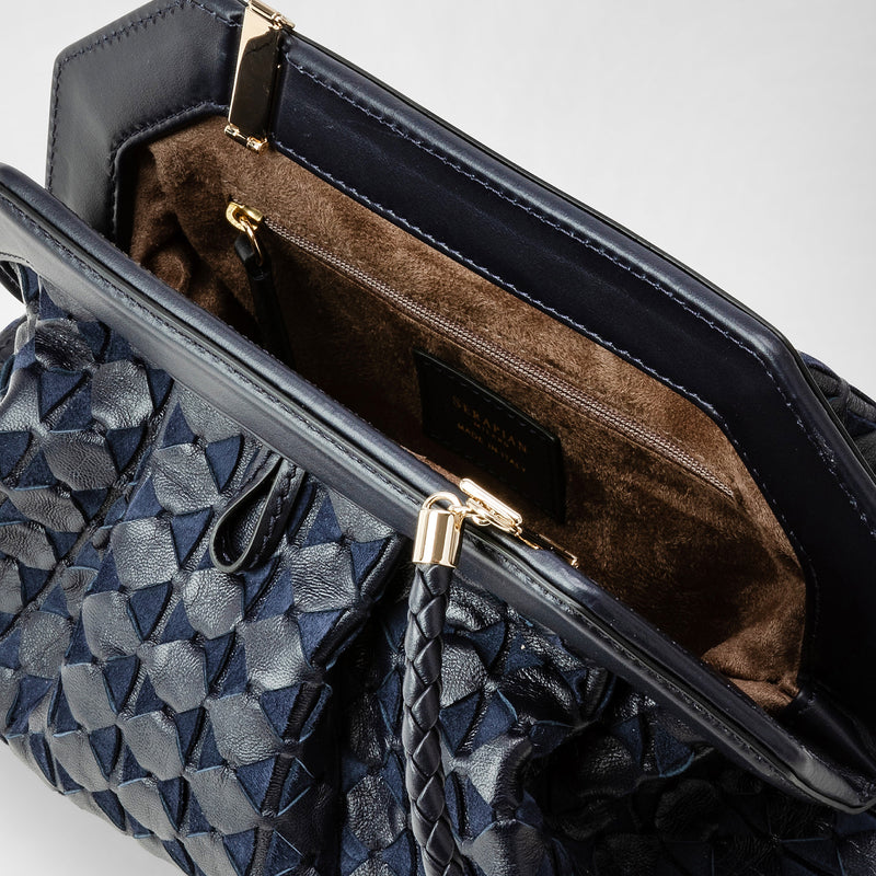 Detail view: SECRET CLUTCH BAG IN MOSAICO features a close-up of midnight blue woven nappa leather, showcasing its unique structure and brown suede-lined interior with a zip pocket.