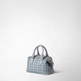 Front view: MINI ANI BAG IN RIBBON MOSAICO stands against a light background; the ice-blue bag features a three-dimensional woven surface, short handles, and gold-tone zipper details.