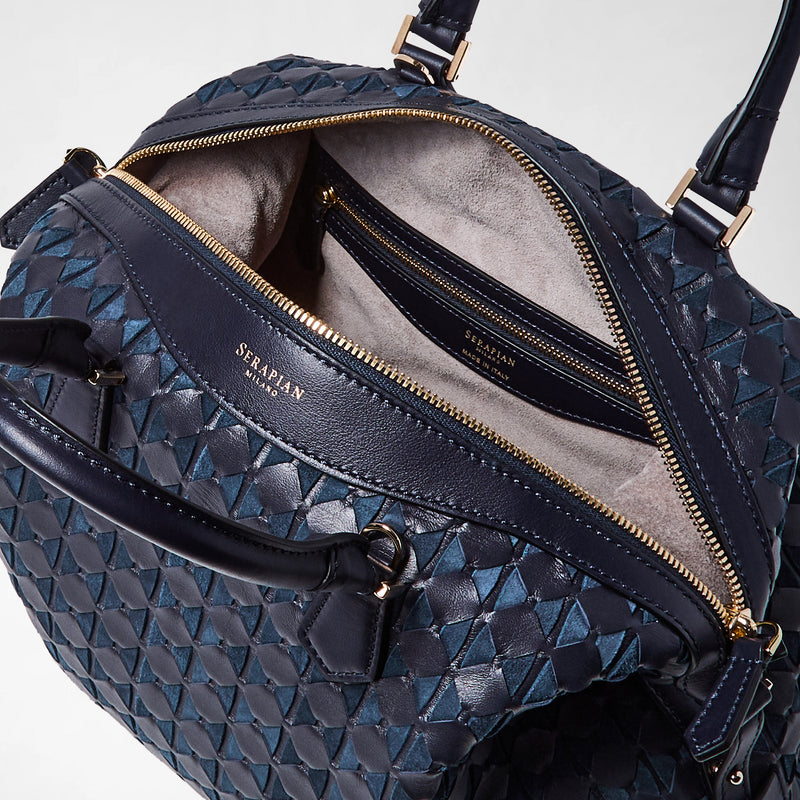 Detail view: ANI BAG IN MOSAICO shows a midnight blue woven leather bag with gold zipper, revealing its beige suede interior and inside zippered pocket labeled &#39;SERAPIAN MILANO&#39;.