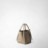 Detail view: MINI BUCKET IN MOSAICO stands at a three-quarter angle against a light background; the sand-colored bag features a Mosaico pattern, knotted handles, and the “SERAPIAN MILANO” logo.