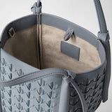 Detail view: MINI BUCKET IN RIBBON MOSAICO shows its light-colored lining and ice-blue woven leather, with “SERAPIAN MILANO” embossed inside.