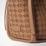 Detail view: MINI BUCKET IN MOSAICO features sandalwood-colored, geometrically woven leather, a stitched edge, and a branded tab reading “SERAPIAN MILANO” against a light background.