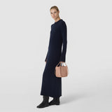 Front view: A woman wears the MINI BUCKET IN MOSAICO in sandalwood-colored woven leather, with short handles and side drawstrings.