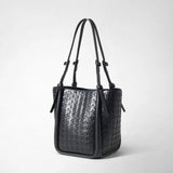 BUCKET IN MOSAICO in frontal view: A black bucket bag in glossy, geometrically embossed leather with long shoulder straps and small knots stands against a neutral studio background.