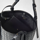 Detail view of BUCKET IN MOSAICO: The black leather bag shows its woven exterior, straps, and dark interior with a “SERAPIAN MADE IN ITALY” label.
