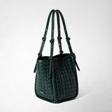 Detail view: BUCKET IN RIBBON MOSAICO is shown at an angle against a light background; the forest-green leather bag features a woven pattern and long straps. The label reads “SERAPIAN MILANO”.