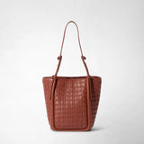 Front view of BUCKET IN MOSAICO: A brick-red leather bag with an intricate woven pattern, a soft silhouette, and long shoulder straps with small knots stands against a light background.
