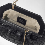 Vista dettagliata: la MINI CLUTCH SECRET IN MOSAICO è aperta e mostra la pelle Mosaico nera, una fodera interna chiara e dettagli della catena color oro. Sull’etichetta si legge «SERAPIAN MILANO MADE IN ITALY».