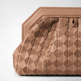 Detail view: MINI SECRET CLUTCH BAG IN MOSAICO features sandal-colored, geometrically woven nappa leather and suede with a carefully stitched edge and a small leather zipper pull against a light background.
