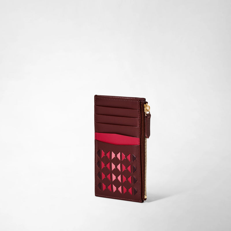Three-quarter view: ZIP CARD CASE IN MOSAICO displays a slim, rosewood-colored leather card case with woven geometric pattern, card slots, and a gold-tone zippered pocket.
