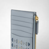 Detail view: ZIP CARD CASE IN MOSAICO shows light blue leather with a woven mosaic pattern, card slots, and a gold zipper against a light background.