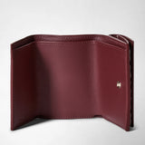 Frontal view: MINI TRI-FOLD WALLET IN MOSAICO shows an open, rosewood-colored mini wallet with smooth nappa leather interior and a single metal snap closure visible.