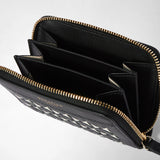 Detail view: The MINI ZIP WALLET IN MOSAICO is open, showing black interior compartments, a gold-tone zipper, and black-and-cream Mosaico leather; “BOTTEGA VENETA” appears on the exterior.
