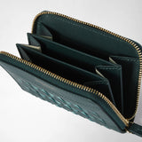 Detail view: MINI ZIP WALLET IN MOSAICO is open, showing a forest-green interior with several compartments, a gold-tone wraparound zipper, and a woven leather exterior.
