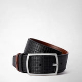Frontal view: REVERSIBLE BELT IN STEPAN 72 displays a black textured belt with a rectangular gunmetal buckle and brown leather inserts, coiled neatly.