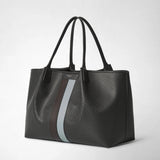Front view: SECRET TOTE BAG IN STEPAN stands against a light background, with an embossed asphalt-gray surface, long leather handles, and brown and ice-blue stripes; label: “SERAPIAN MILANO”.