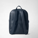 Rear view: BACKPACK IN STEPAN shows two wide shoulder straps, a carry handle, and an embossed S pattern on dark blue material, standing alone against a light background.