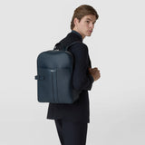 BACKPACK IN STEPAN worn over a man's shoulder; front view of the ocean-blue backpack with an embossed pattern, leather details, and a wraparound zipper against a light background.