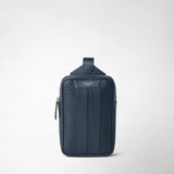 Front view: SLING BACKPACK IN STEPAN stands upright against a light background; navy embossed material and leather details, with the visible lettering “SERAPIAN MILANO”.