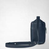 Rear view: SLING BACKPACK IN STEPAN stands upright; its ocean-blue embossed surface and navy leather strap are visible against a light background.