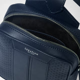 Detail view: SLING BACKPACK IN STEPAN with open main compartment, silver zipper, navy Stepan embossing and leather details; “SERAPIAN MILANO” appears on the front.