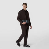 Front view: A man holds the WASHBAG IN STEPAN in front of his body; its asphalt-gray textured surface with an ice-blue leather strip is visible in the bright studio.