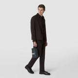 Front view: A man carries the WASHBAG IN STEPAN by its handle; the asphalt-gray bag with S-etching, zipper, and ice-blue accent is shown against a light background.